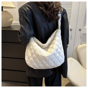 Quilted white crossbody bag with puffed semi-moon shape shown on a female model