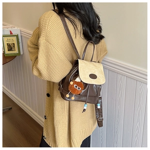 Detail of vintage denim backpack with plush pendant and brown leather patchwork design