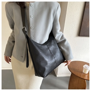 Close-up of black leather hobo bag with wrinkled texture and silver adjustable buckle