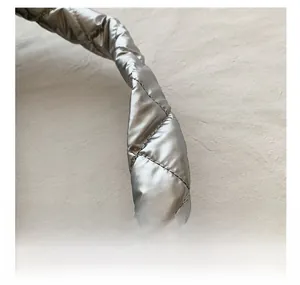 Gros plan sur la bandoulière matelassée argentée avec finition métallique et couture