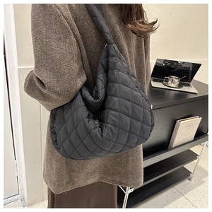 Quilted black nylon tote bag shown on a model in a minimalist office setting