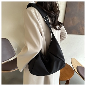 Détail d'un sac bandoulière croissant noir matelassé avec boucle réglable en argent