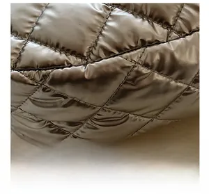 Détail du matelassage en losange précis et de la texture métallique argentée du sac