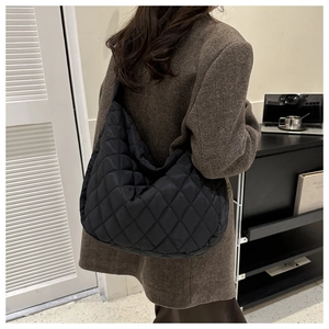 Close-up of black quilted nylon tote bag with geometric rhombus stitching detail