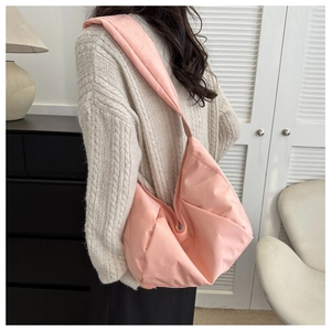 Vue détaillée du sac hobo matelassé rose porté à l'épaule avec une texture nuageuse