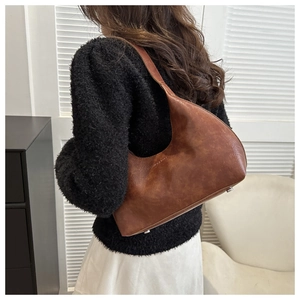 Detail of dark brown leather crescent bag with metal protective feet and vintage texture
