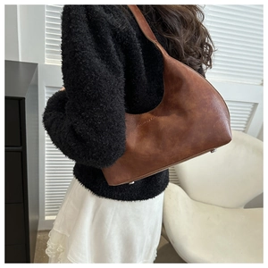 Detailed side view of a brown retro hobo bag worn by a model in a minimalist setting