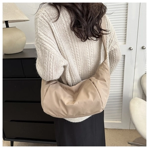 Détail du sac croissant en nylon beige avec texture plissée et finition mate