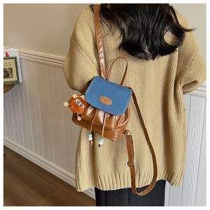 Vintage denim patchwork mini backpack with plush charm and drawstring closure shown on model