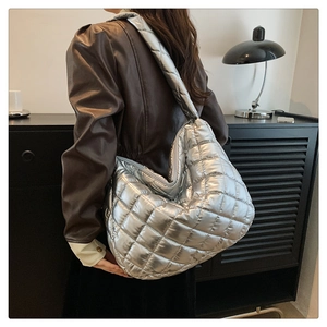 Sac hobo matelassé argenté porté par un mannequin en veste de cuir marron foncé