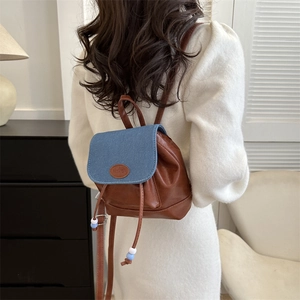 Vintage mini backpack in brown leather and blue denim contrast, worn by a model