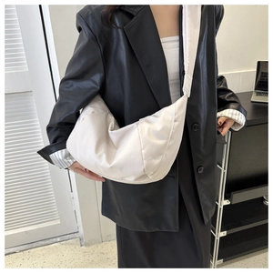 Gros plan d'un sac bandoulière demi-lune crème avec nylon rembourré et texture plissée