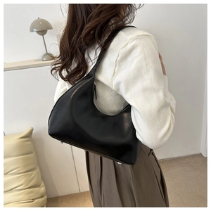 Detail of black glossy hobo bag with silver bottom studs and fashion logo on modern background