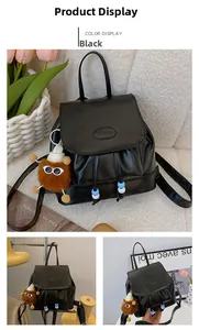 Detail of black leather travel backpack with drawstring pom-poms and plush charm
