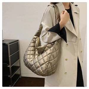Détail du sac hobo matelassé doré champagne porté par un mannequin en trench-coat