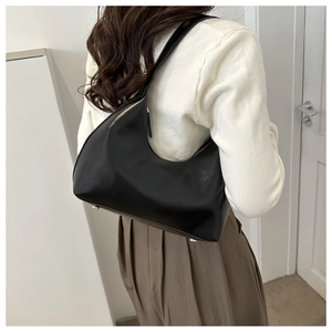 Detail shot of black leather crescent underarm bag with silver feet and embossed logo