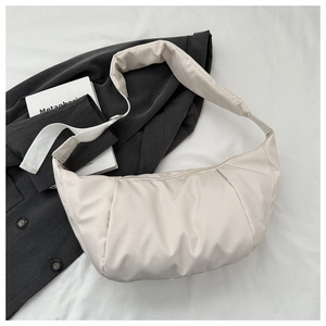 Gros plan détaillé du sac croissant beige en nylon plissé avec bandoulière rembourrée