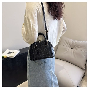 Elegant black crocodile-patterned shell bag with golden hardware and adjustable strap