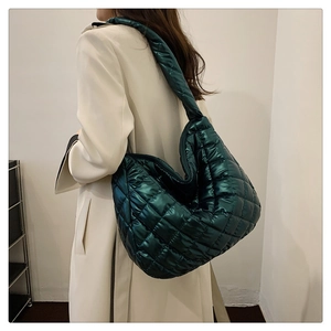 Détail du sac matelassé vert foncé avec finition métallique brillante et surpiqûres