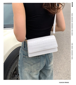 White crocodile pattern crossbody bag shown on model in an outdoor street setting