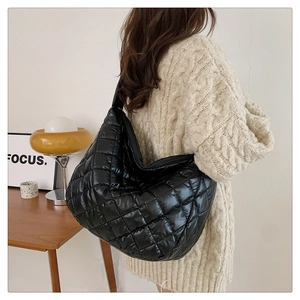 Sac à bandoulière matelassé noir porté par un mannequin dans un décor minimaliste