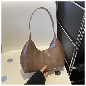 Vintage brown leather underarm bag with moon shape and Fashion & Bags logo in hand