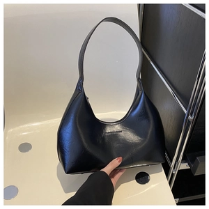 Close-up of black glossy leather underarm bag featuring Fashion & Bags logo print