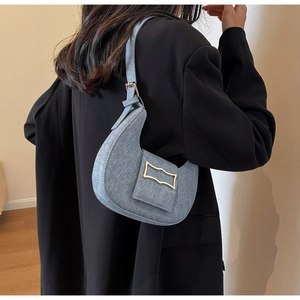 Detail of light blue crescent saddle bag with gold buckle on black blazer