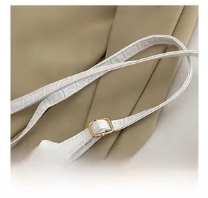 Detail of white crocodile pattern faux leather shoulder strap with gold metal buckle
