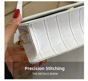 Close-up of white crocodile pattern leather texture with precision stitching and gold D-ring