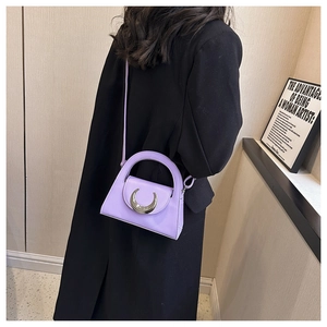Detail of purple leather handbag featuring a silver crescent moon buckle on a black coat
