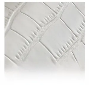 Detailed macro view of white crocodile pattern embossed leather texture on a small bag