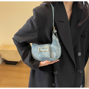 Detail of light blue denim crescent underarm bag with gold buckle on black blazer