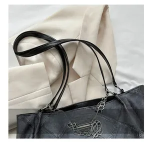 Close-up of black textured leather tote bag with silver metal chain and thin handles