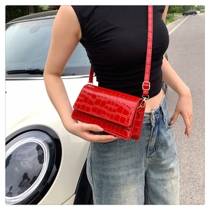 Close-up of red crocodile embossed crossbody bag with golden metal hardware detail