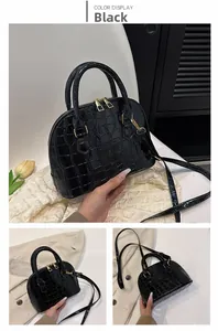 Detail of black crocodile texture on shell handbag with golden hardware and strap