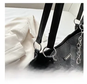 Detail of checkered tote bag with silver ring connector and metallic chain strap