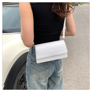 Outdoor shot of a white crocodile texture crossbody bag with gold hardware details