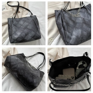 Close-up of large capacity patchwork tote bag with chain strap and denim texture detail