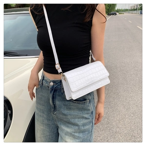 Close-up of white crocodile texture crossbody bag with adjustable gold buckle strap