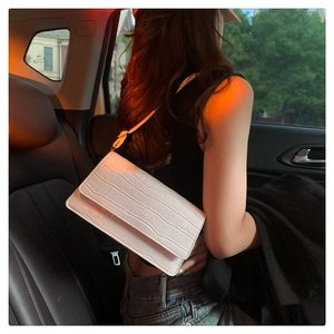 Detail of white crocodile pattern embossed leather bag with sleek shoulder strap