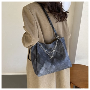 Detail of grey checkered tote bag with silver chain and heart charm on wool coat