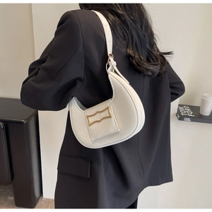 Minimalist cream crescent moon bag with gold buckle on a black blazer context