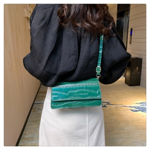 Green crocodile pattern crossbody bag detail worn by a model in a real-life setting