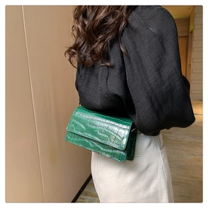 Detail of green crocodile embossed faux leather shoulder bag texture and gloss