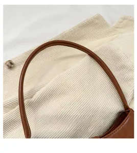 Detailed close-up of brown leather handle with neat stitching on minimalist shoulder bag