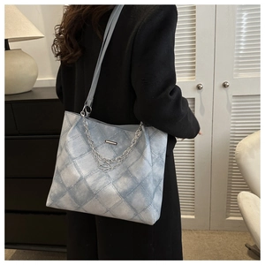 Close-up of light blue denim tote bag featuring quilted patterns and silver chain straps
