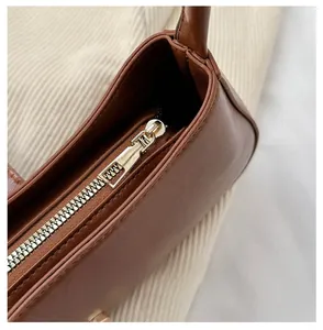 Detail of smooth gold-tone zipper on retro brown synthetic leather shoulder bag