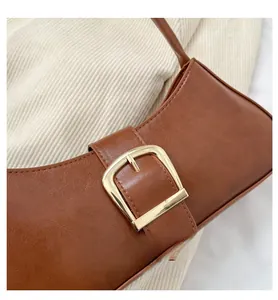 Detail of vintage brown baguette bag featuring a stylish large gold buckle and leather strap