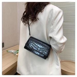 Minimalist black crocodile embossed crossbody bag shown on a model in a cozy room